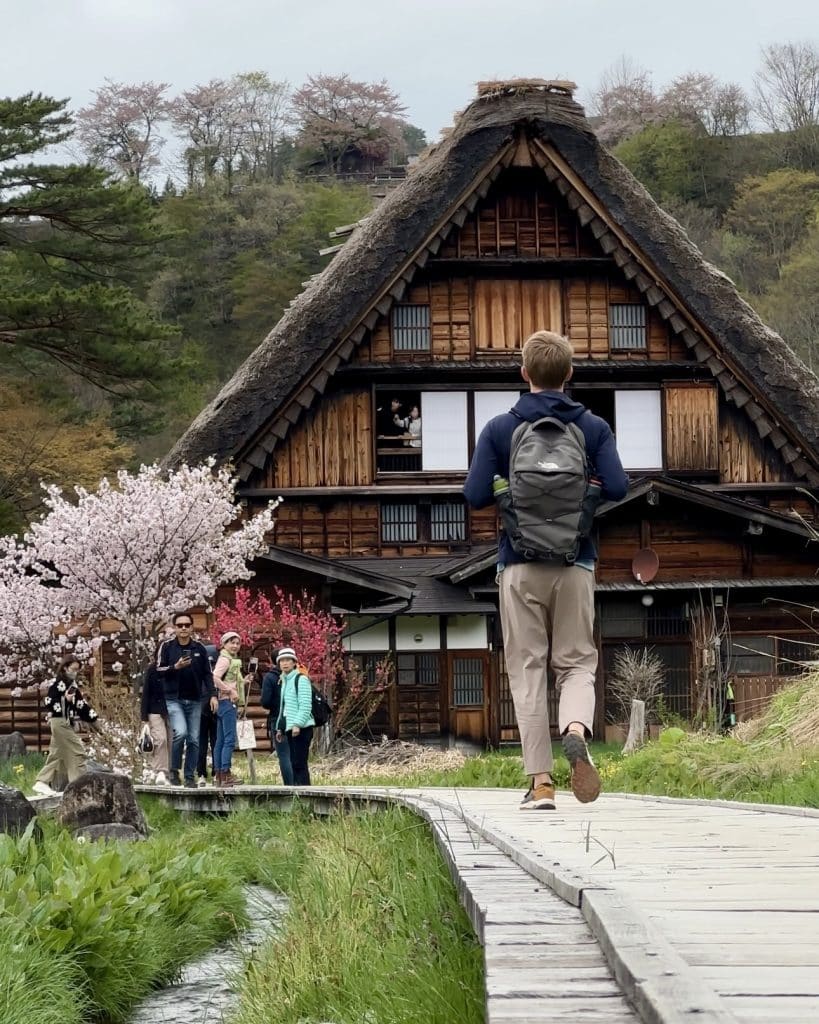 Homme marchant vers une maison de paille dans le village de Shirakawa